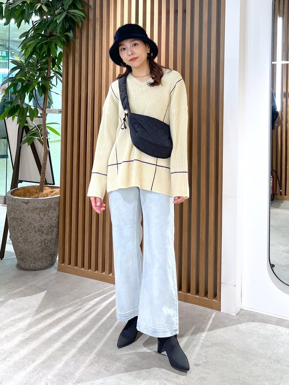 ブラック系のショルダーバッグ、ホワイト系のニット/セーター、ブルー系のデニムパンツを着用したレディースの冬コーディネートの6枚目の写真