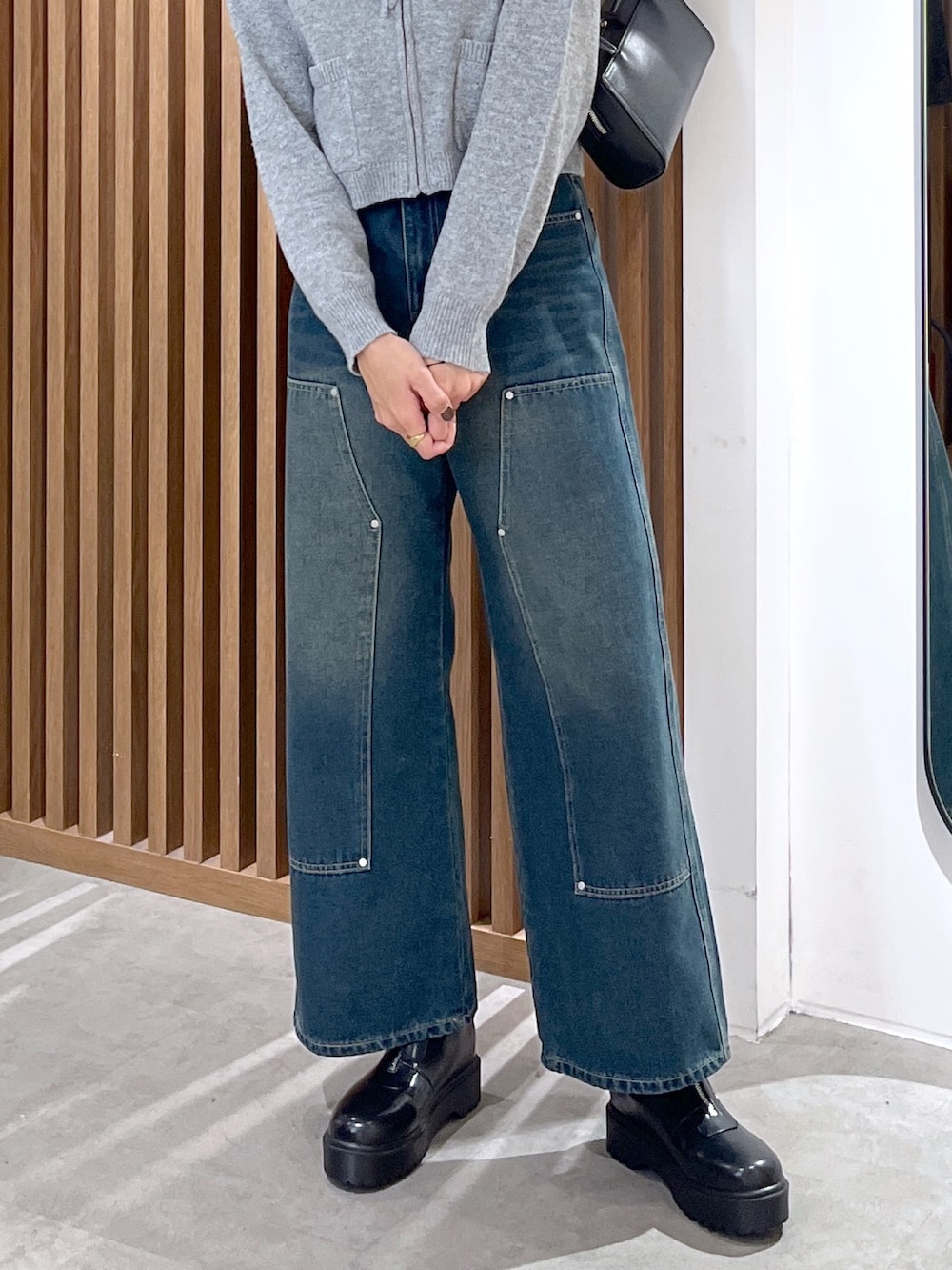 グレー系のワンピース、ブルー系のデニムパンツ、ブラック系のブーツを着用したレディースの冬コーディネートの7枚目の写真