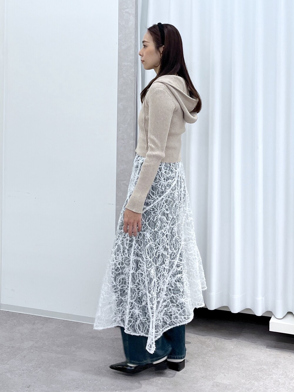 ベージュ系のニット/セーター、ブラウン系のハンドバッグ、ブルー系のデニムパンツを着用したレディースの冬コーディネートの5枚目の写真