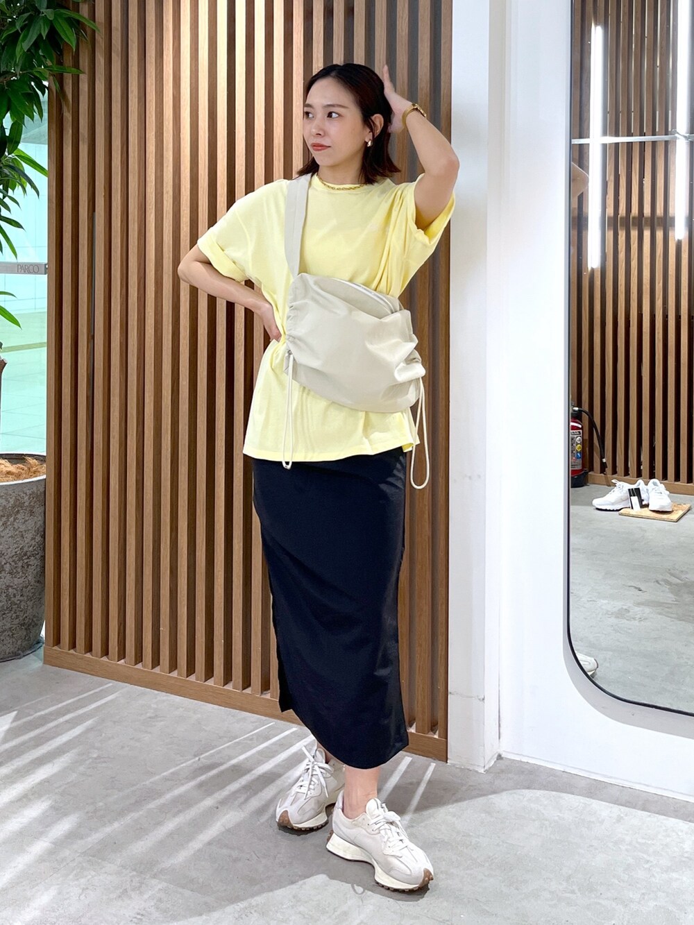 イエロー系のTシャツ/カットソー、ホワイト系のショルダーバッグ、ブラック系のスカートを着用したレディースの春コーディネートの3枚目の写真