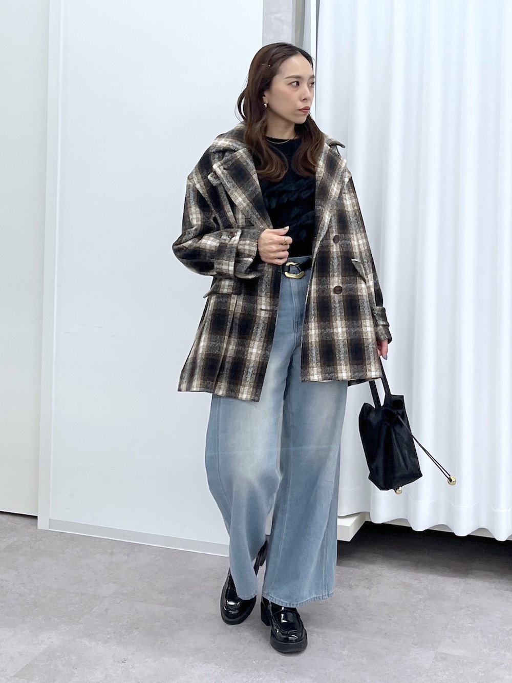 ブラック系のショルダーバッグ、ブルー系のデニムパンツ、ブラック系のニット/セーターを着用したレディースの冬コーディネートの6枚目の写真