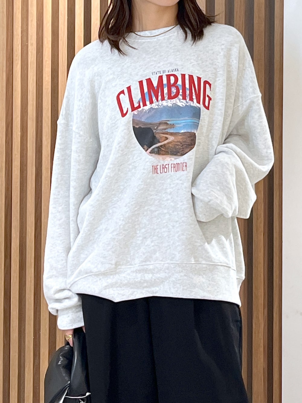 ホワイト系のスウェット、ブラック系のショルダーバッグ、ブラック系のスラックスを着用したレディースの秋コーディネートの6枚目の写真