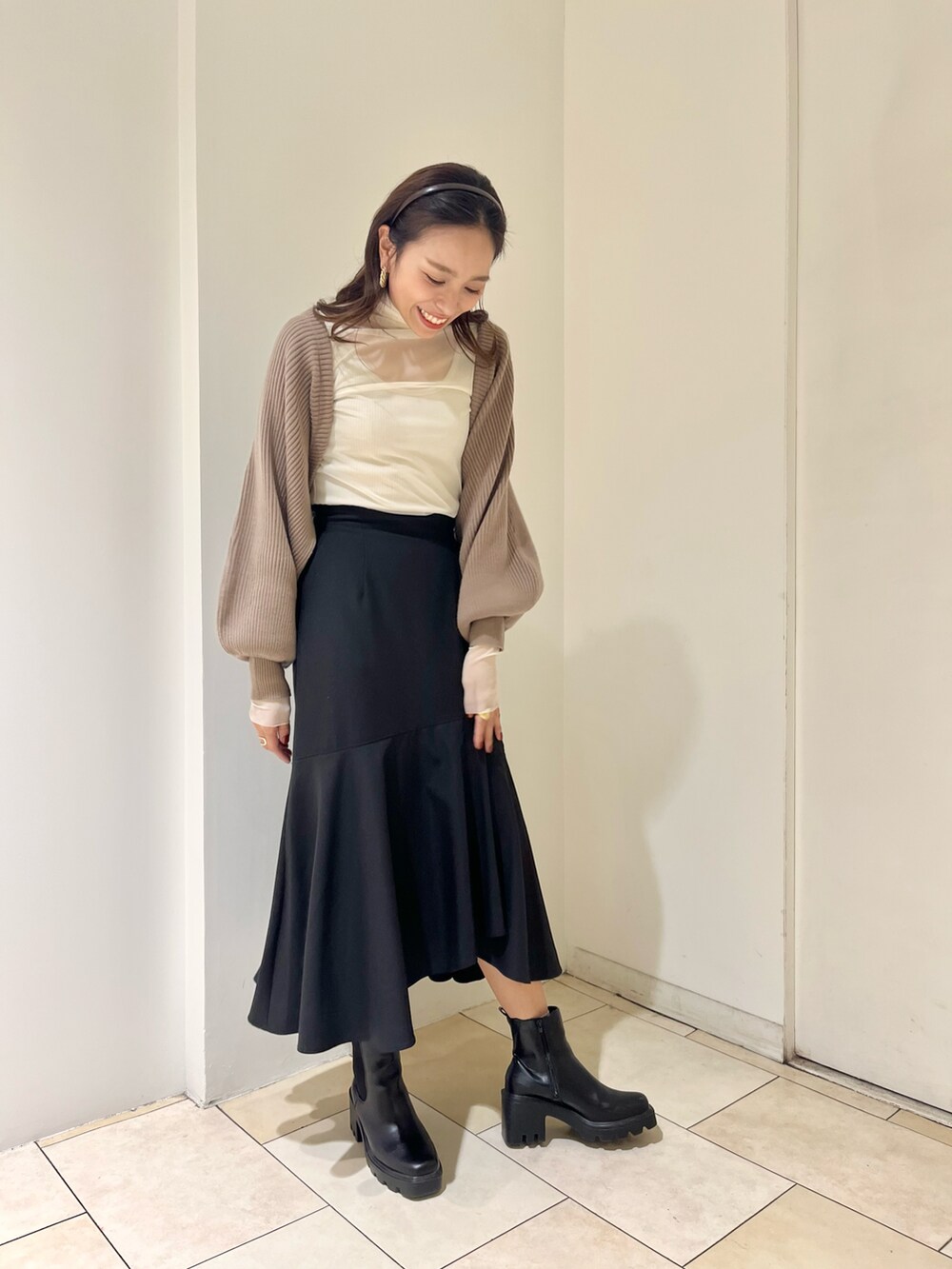 ブラウン系のカーディガン/ボレロ、ブラック系のスカート、ホワイト系のTシャツ/カットソーを着用したレディースの秋コーディネートの2枚目の写真