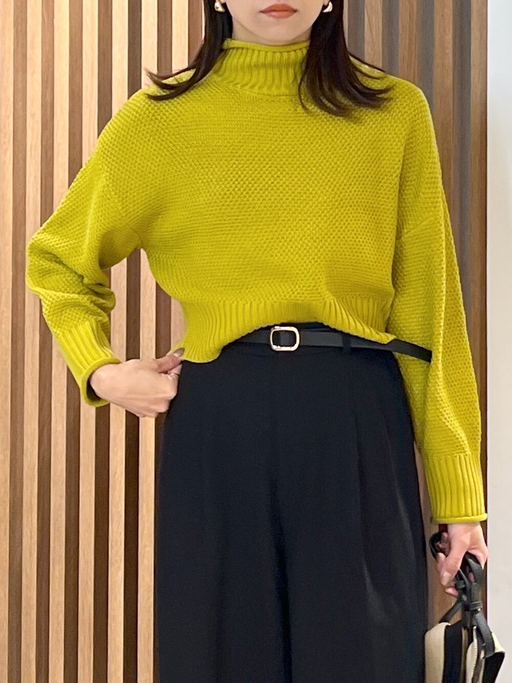 イエロー系のニット/セーター、ブラック系のスラックス、ブラック系のショルダーバッグを着用したレディースの冬コーディネートの6枚目の写真