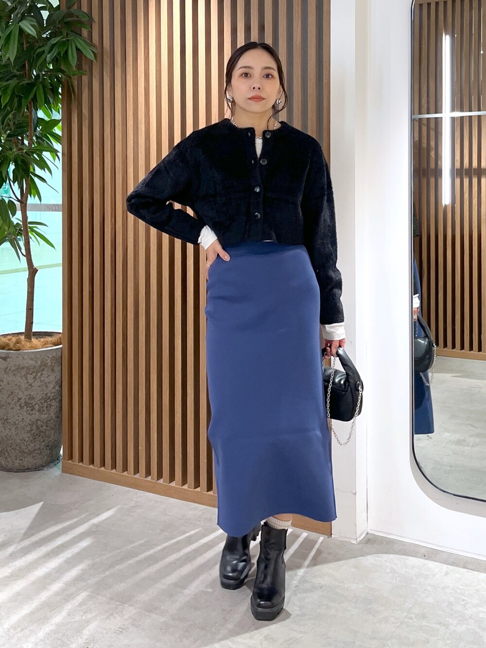 ブラック系のカーディガン/ボレロ、ブラック系のショルダーバッグ、ブルー系のスカートを着用したレディースの冬コーディネートの8枚目の写真