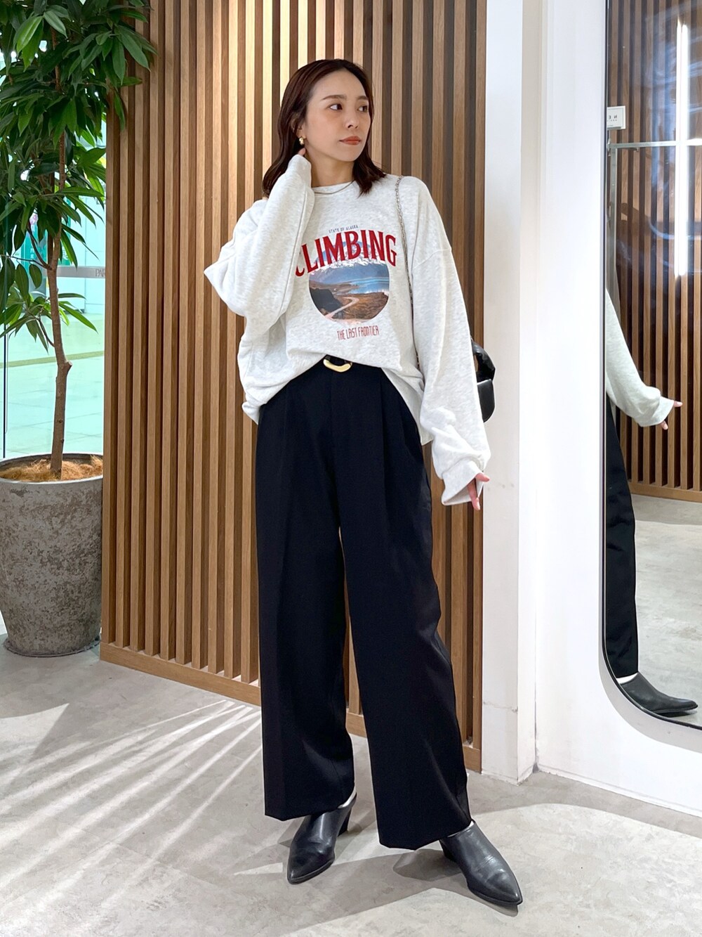 ホワイト系のスウェット、ブラック系のショルダーバッグ、ブラック系のスラックスを着用したレディースの秋コーディネートの3枚目の写真