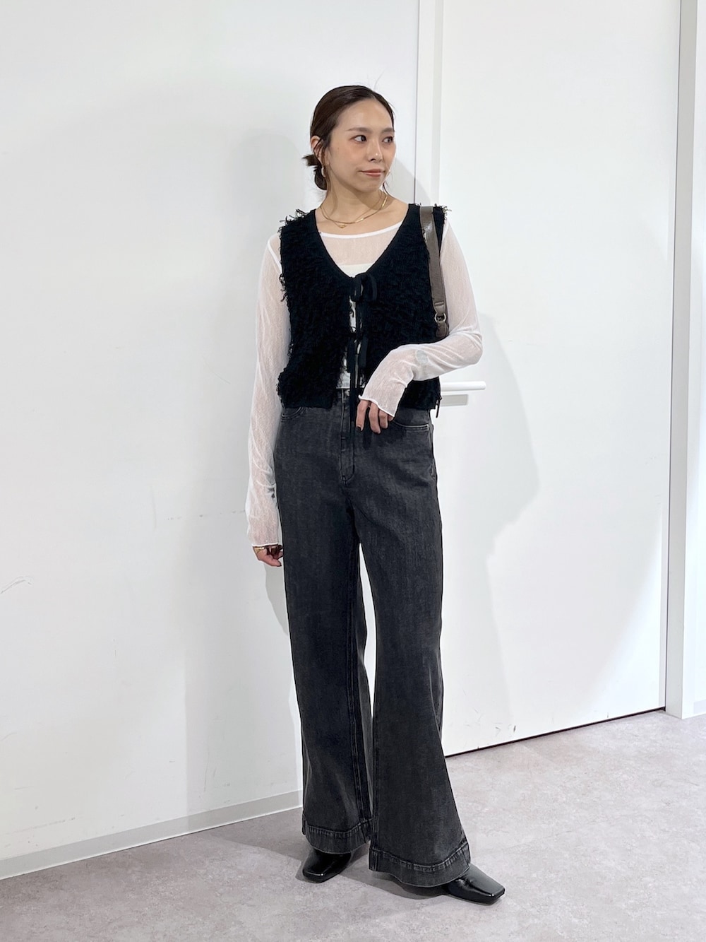 ブラウン系のショルダーバッグ、ブラック系のニット/セーター、ホワイト系のTシャツ/カットソーを着用したレディースの夏コーディネートの8枚目の写真