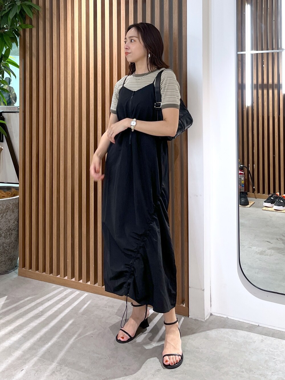 グリーン系のTシャツ/カットソー、ブラック系のショルダーバッグ、ブラック系のサンダルを着用したレディースの春コーディネートの8枚目の写真