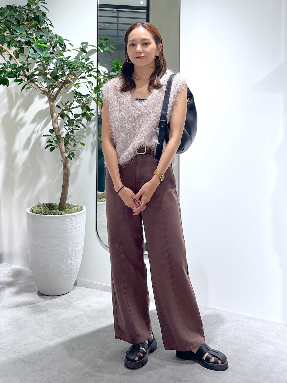ベージュ系のニット/セーター、ブラック系のハンドバッグ、ブラウン系のデニムパンツを着用したレディースの夏コーディネートの4枚目の写真