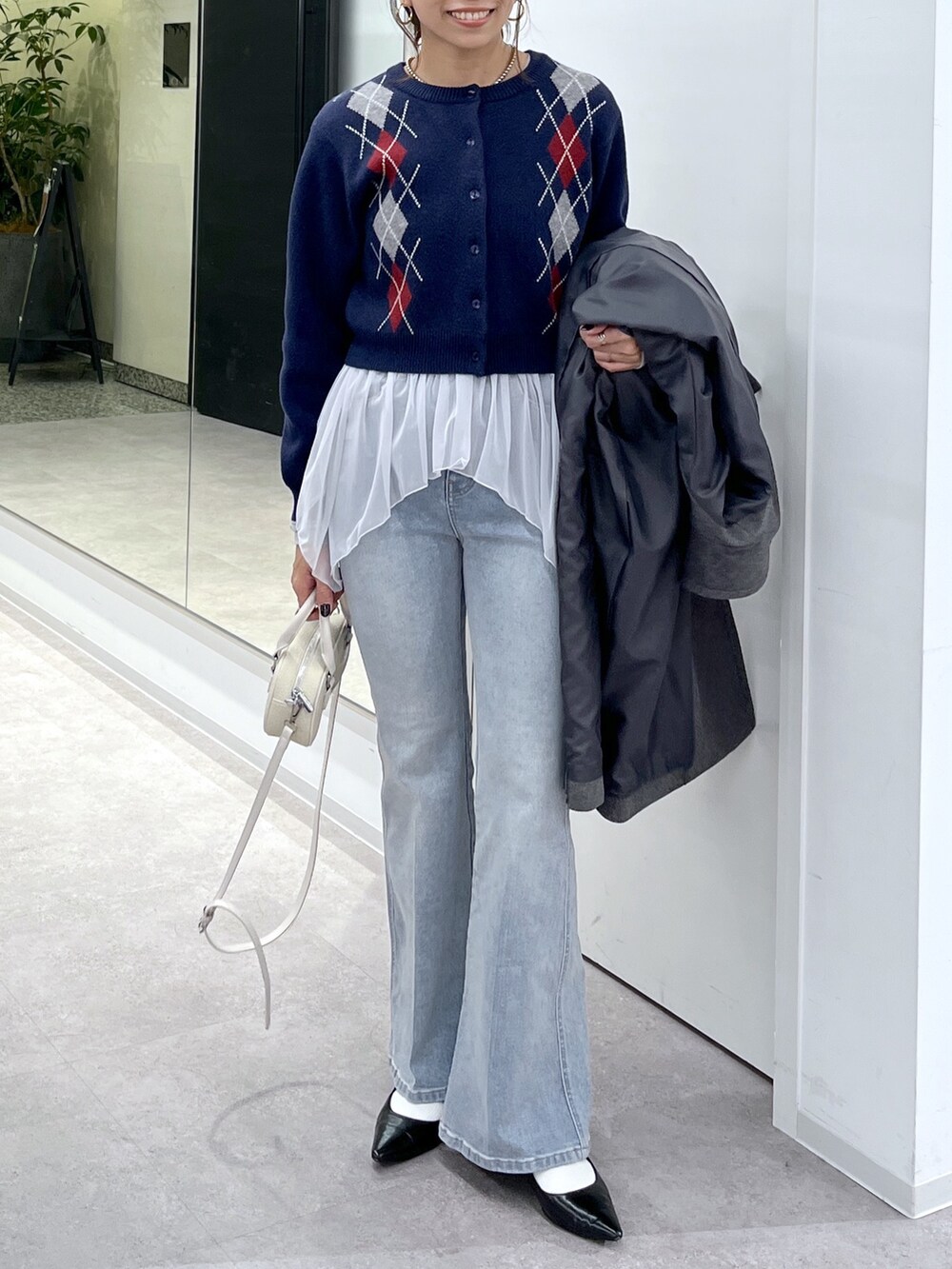 ホワイト系のTシャツ/カットソー、グレー系のステンカラーコート、ブルー系のニット/セーターを着用したレディースの秋コーディネートの4枚目の写真