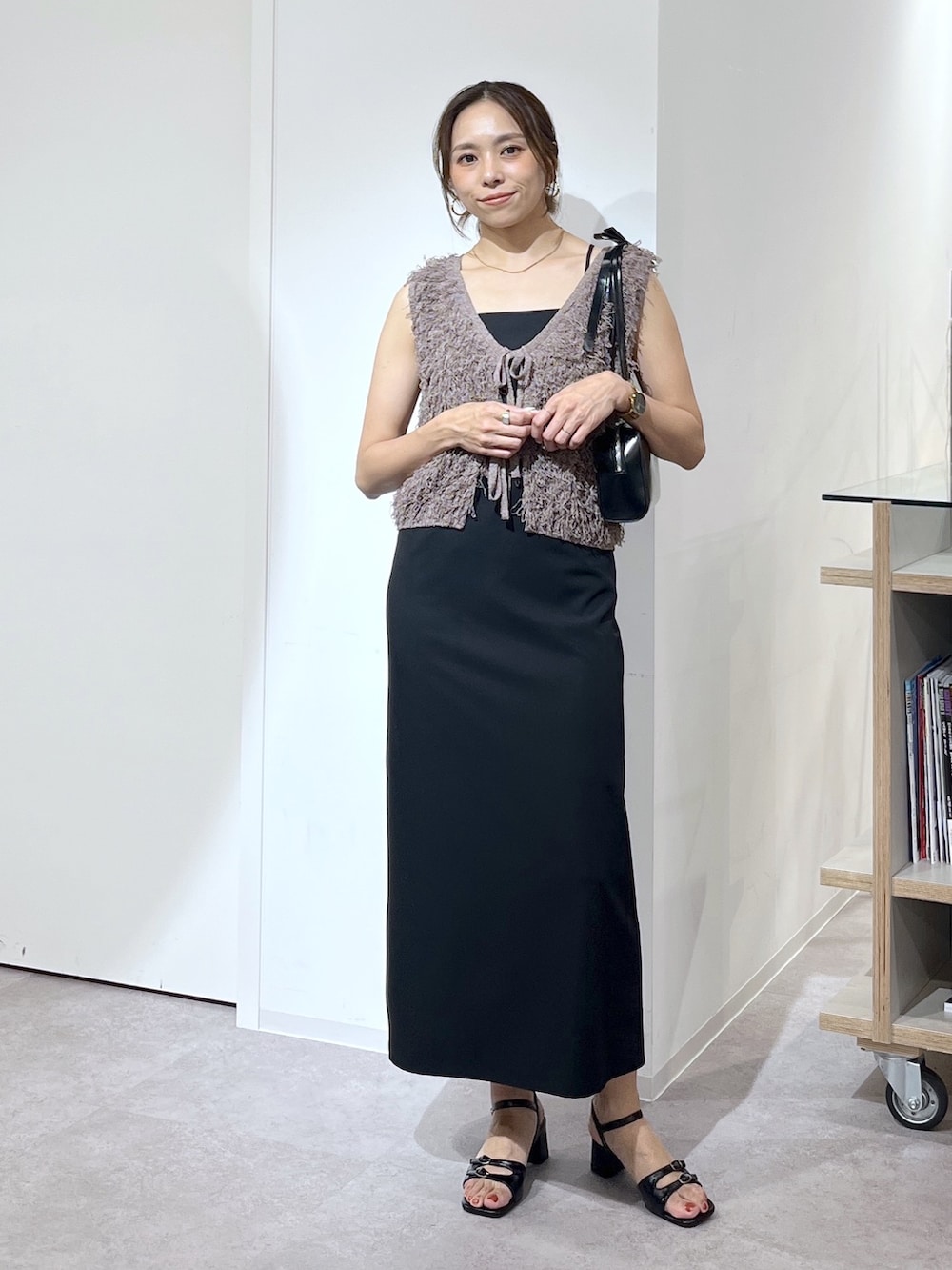 ブラック系のショルダーバッグ、ブラウン系のニット/セーター、ブラック系のワンピースを着用したレディースの夏コーディネートの2枚目の写真