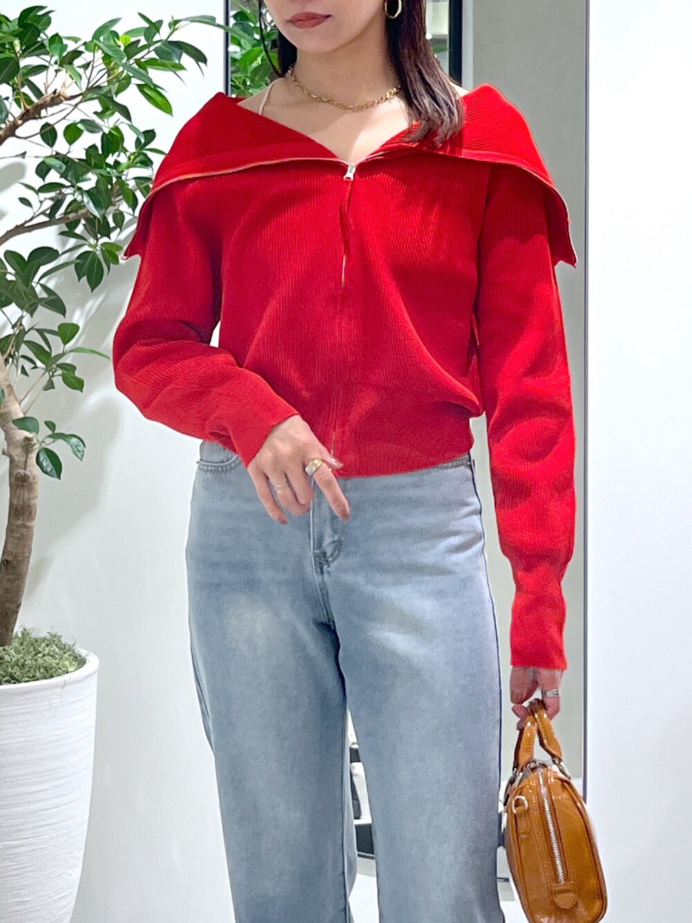 レッド系のニット/セーター、ブルー系のデニムパンツ、ベージュ系のショルダーバッグを着用したレディースの春コーディネートの10枚目の写真