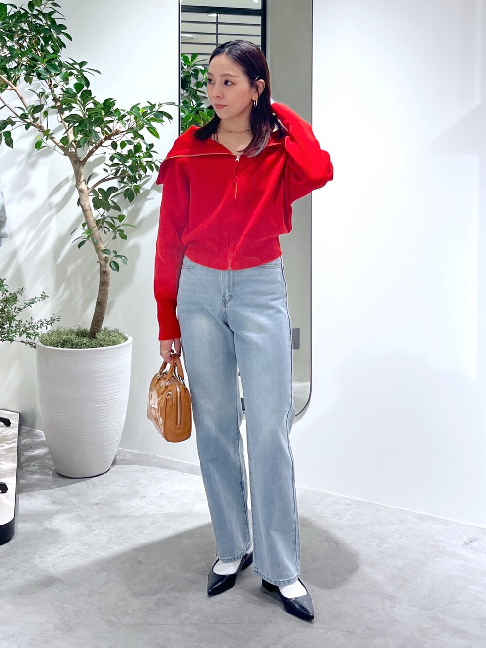 レッド系のニット/セーター、ブルー系のデニムパンツ、ベージュ系のショルダーバッグを着用したレディースの春コーディネートの9枚目の写真