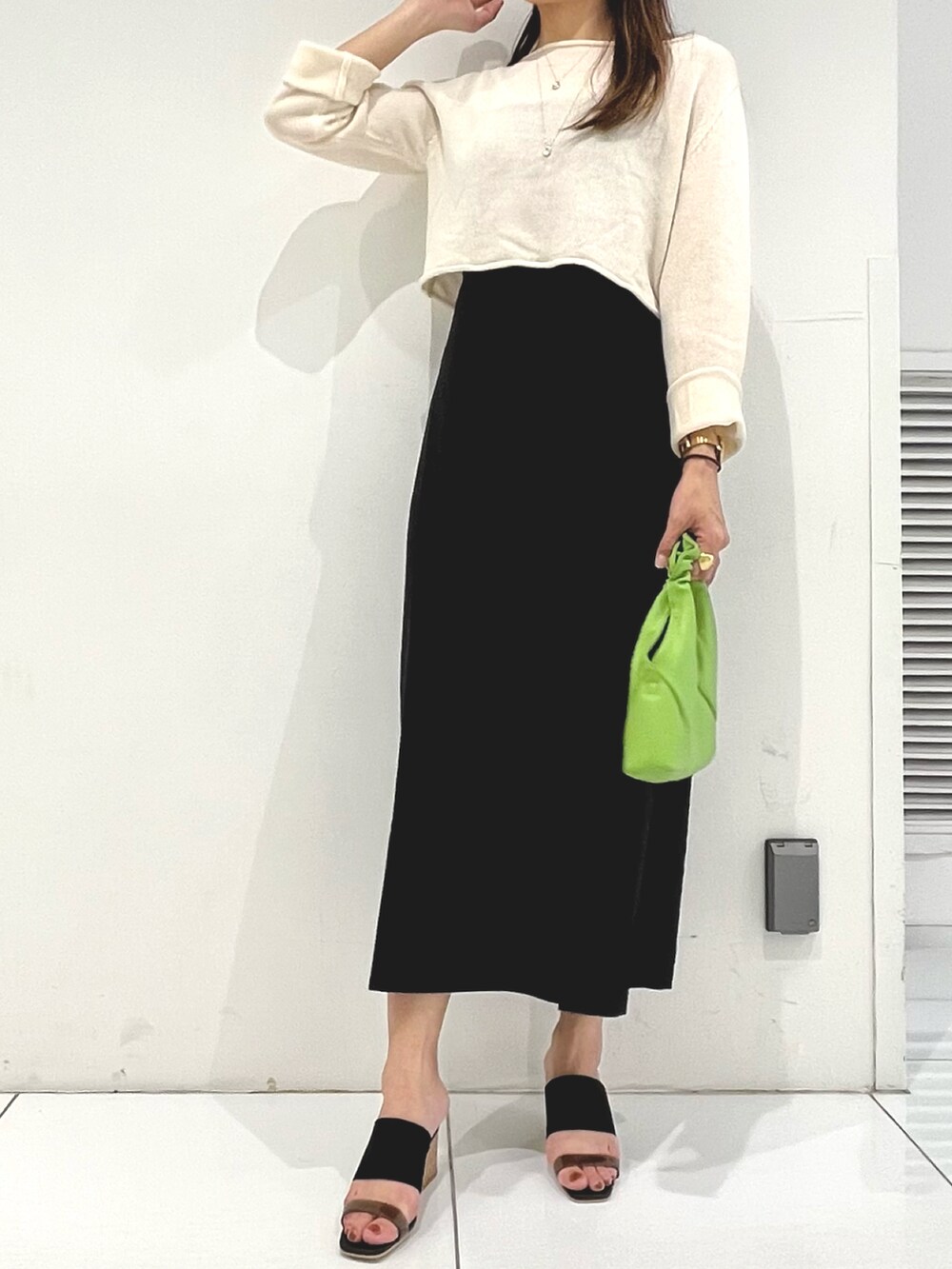 ホワイト系のニット/セーター、ブラック系のワンピース、ブラック系のサンダルを着用したレディースの春コーディネートの2枚目の写真