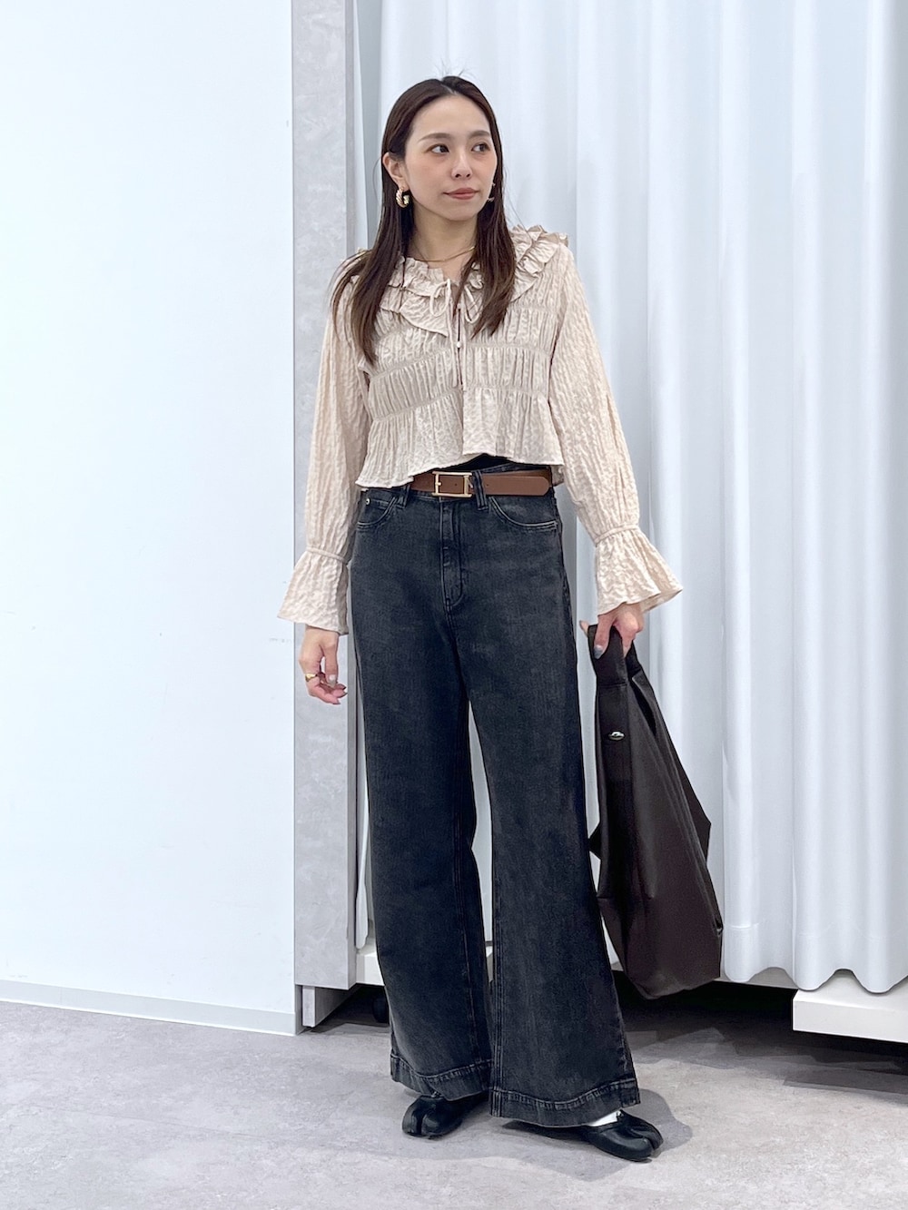 ベージュ系のシャツ/ブラウス、ブラウン系のトートバッグ、ブラック系のデニムパンツを着用したレディースの冬コーディネートの2枚目の写真