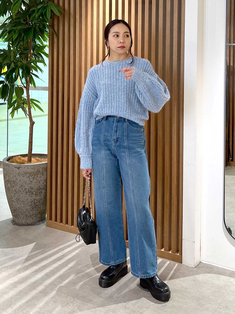ブルー系のニット/セーター、ブルー系のデニムパンツ、ブラック系のハンドバッグを着用したレディースの冬コーディネートの8枚目の写真