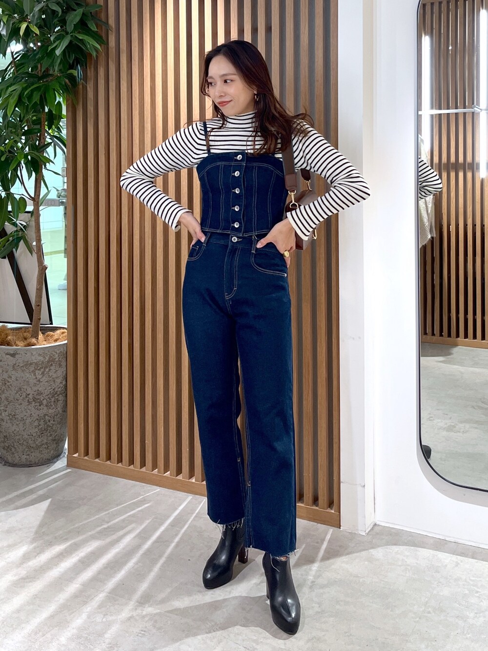 ブラック系のブーツ、ブルー系のデニムパンツ、ブラウン系のショルダーバッグを着用したレディースの冬コーディネートの7枚目の写真