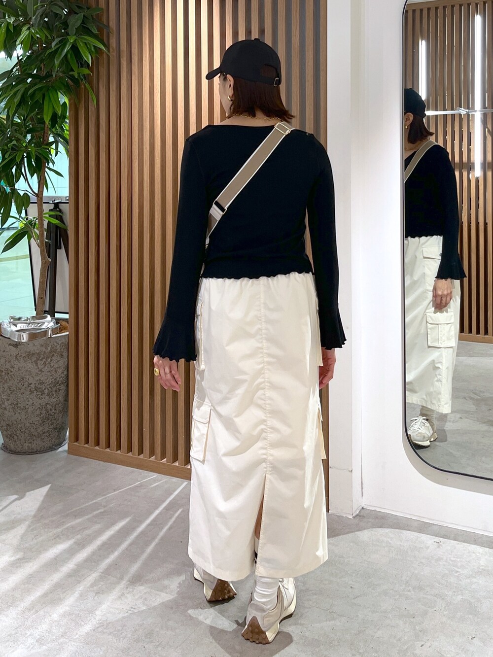ホワイト系のボディバッグ/ウエストポーチ、ブラック系のトップス、ホワイト系のスカートを着用したレディースの春コーディネートの7枚目の写真