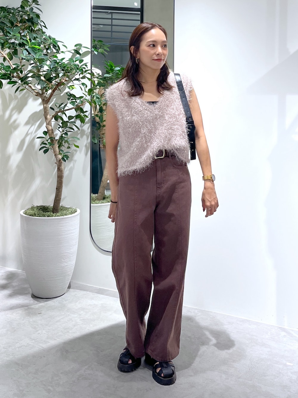 ベージュ系のニット/セーター、ブラック系のハンドバッグ、ブラウン系のデニムパンツを着用したレディースの夏コーディネートの3枚目の写真