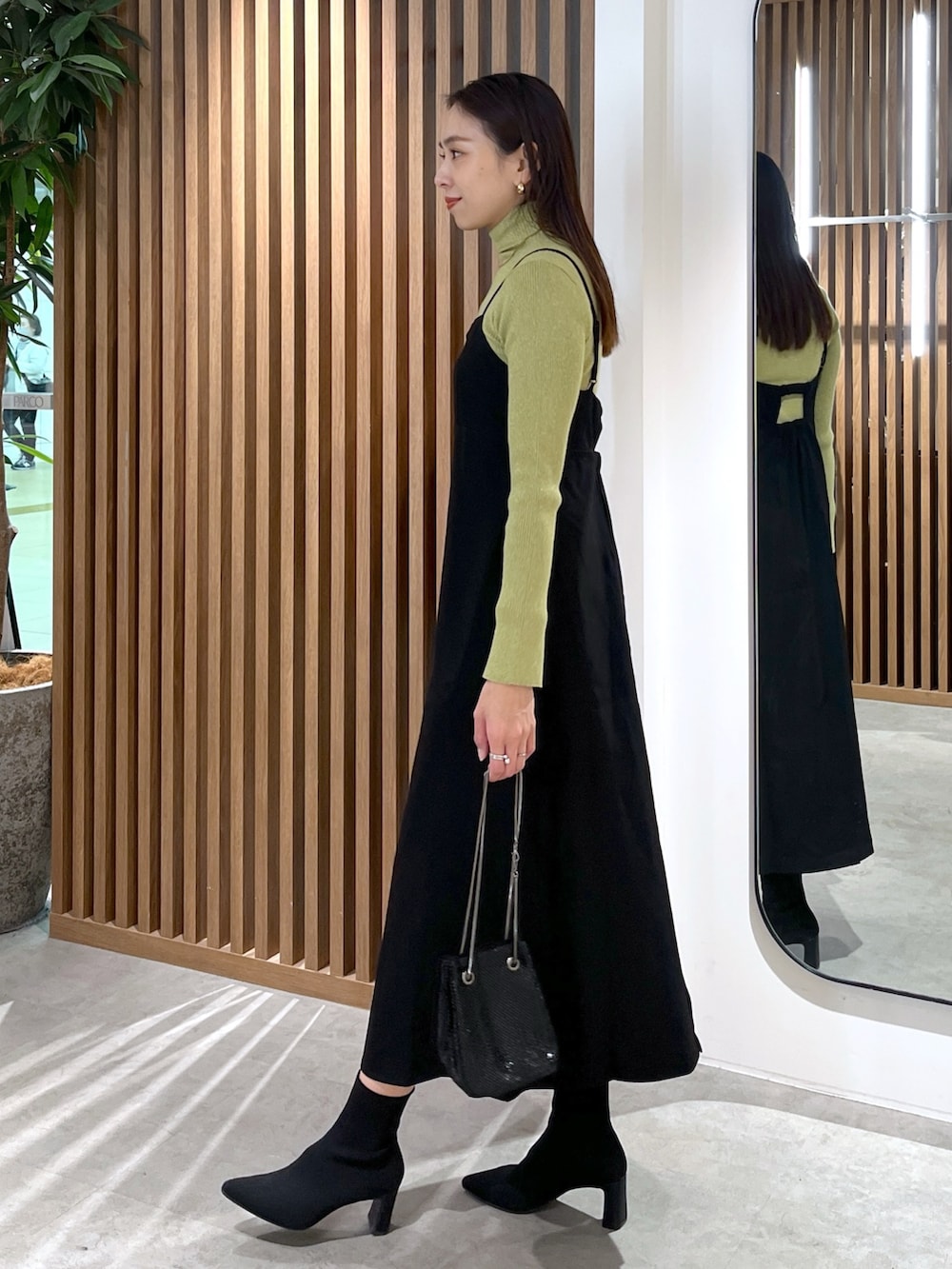 ブラック系のショルダーバッグ、ブラック系のワンピース、グリーン系のニット/セーターを着用したレディースの冬コーディネートの9枚目の写真
