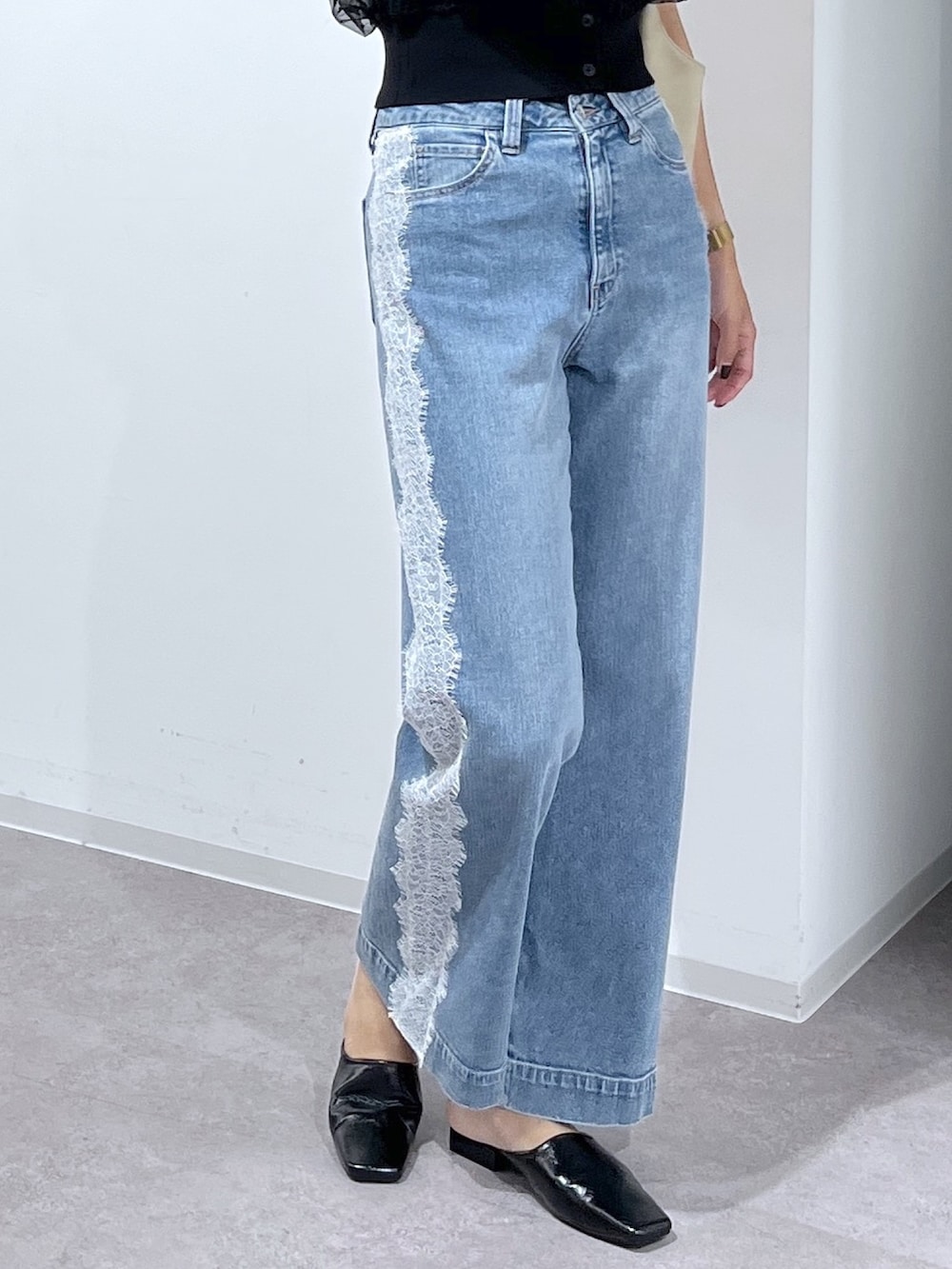 ブラック系のニット/セーター、ブルー系のデニムパンツ、ベージュ系のトートバッグを着用したレディースの夏コーディネートの4枚目の写真