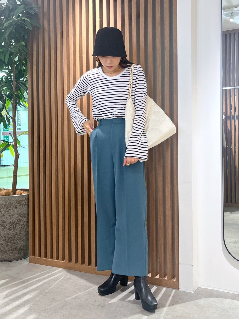 グリーン系のスラックス、ブラック系のTシャツ/カットソー、ホワイト系のトートバッグを着用したレディースの秋コーディネートの4枚目の写真