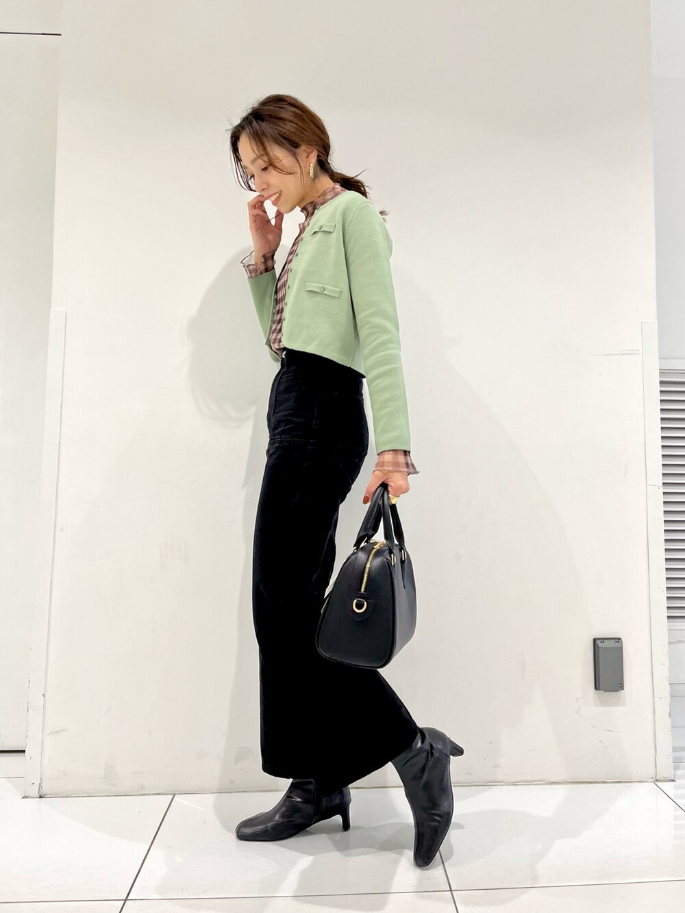 ブラック系のボストンバッグ、グリーン系のカーディガン/ボレロ、ブラウン系のTシャツ/カットソーを着用したレディースの秋コーディネートの2枚目の写真