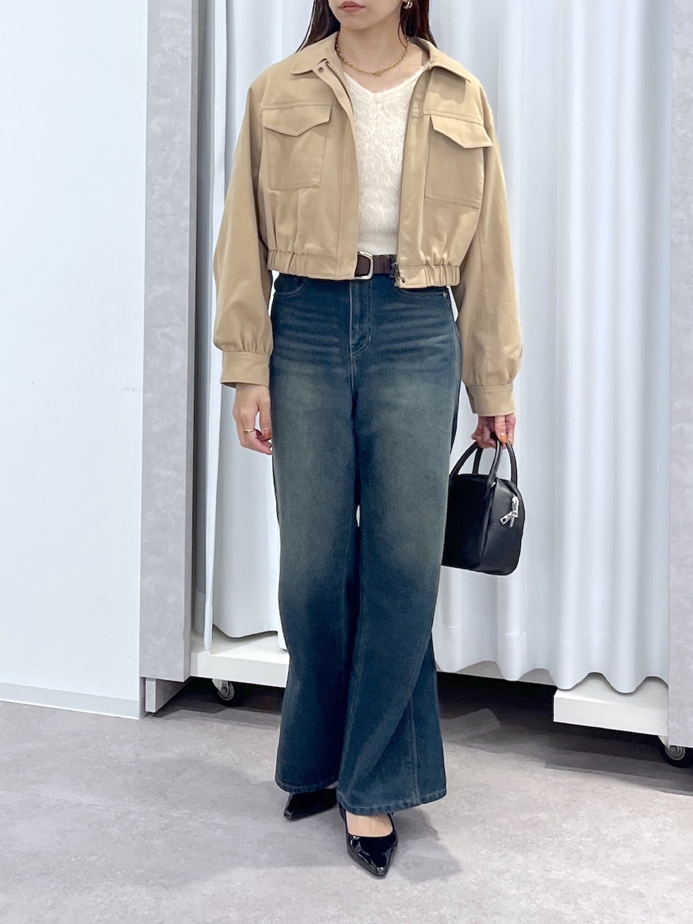 ベージュ系のブルゾン、ホワイト系のニット/セーター、ブルー系のデニムパンツを着用したレディースの春コーディネートの5枚目の写真