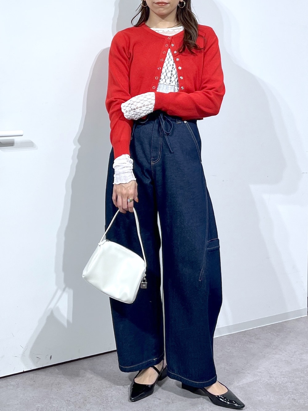 ホワイト系のTシャツ/カットソー、レッド系のニット/セーター、ブルー系のデニムパンツを着用したレディースの春コーディネートの7枚目の写真