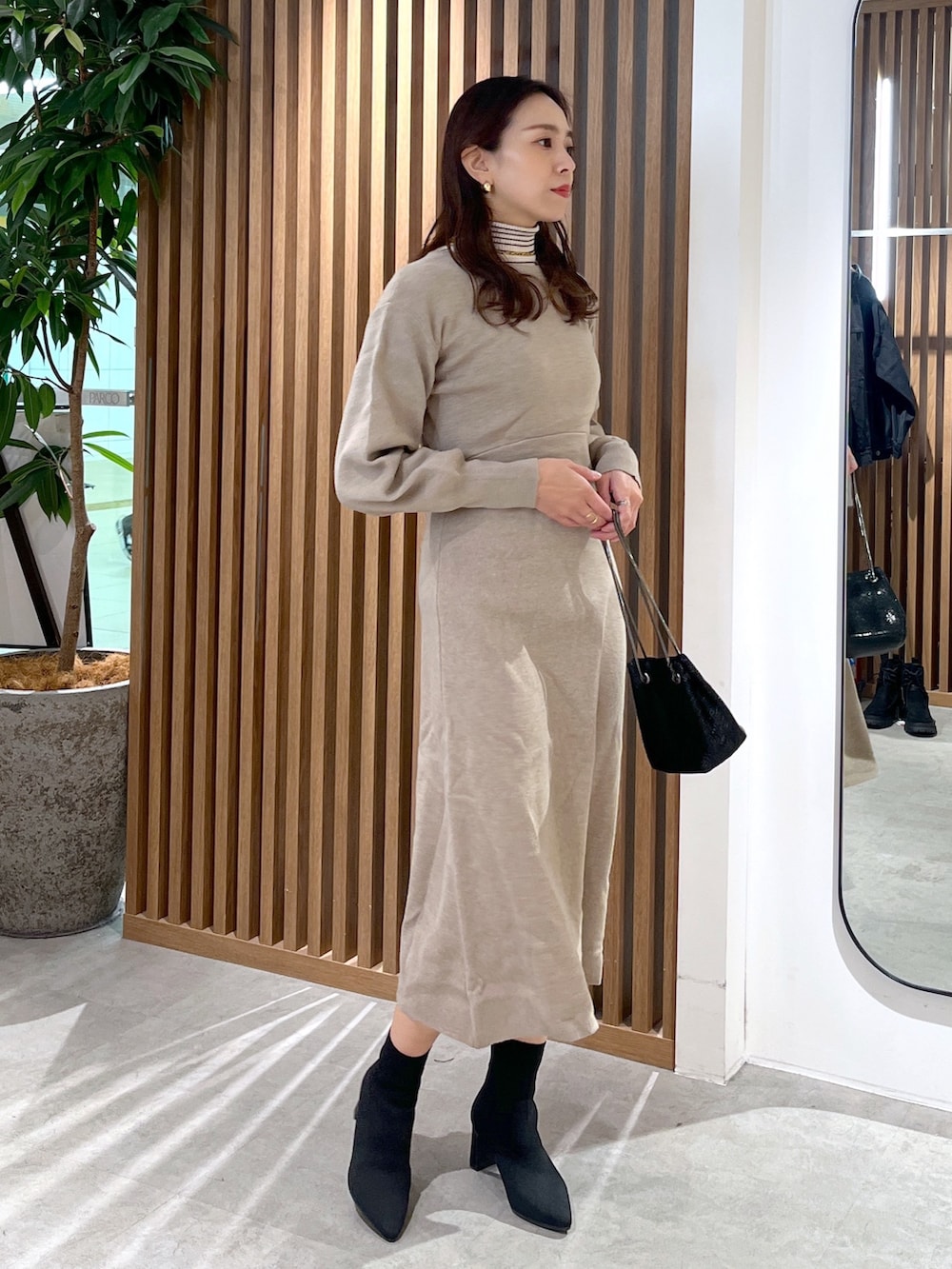 ブラック系のショルダーバッグ、ベージュ系のワンピース、ホワイト系のニット/セーターを着用したレディースの冬コーディネートの3枚目の写真