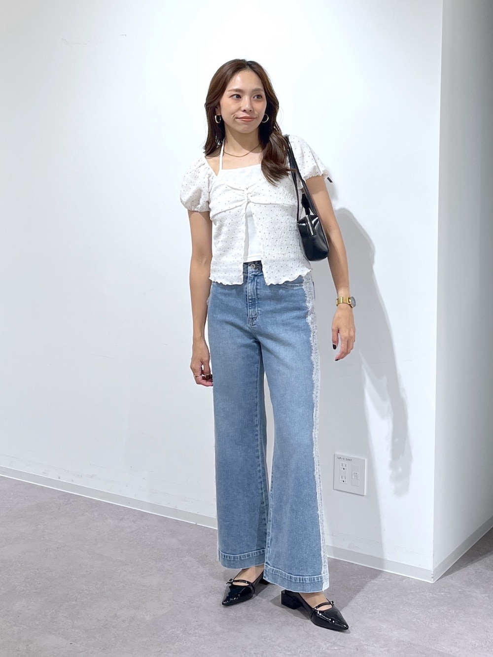 ブラック系のショルダーバッグ、ブラック系のパンプス、ブルー系のデニムパンツを着用したレディースの夏コーディネートの2枚目の写真