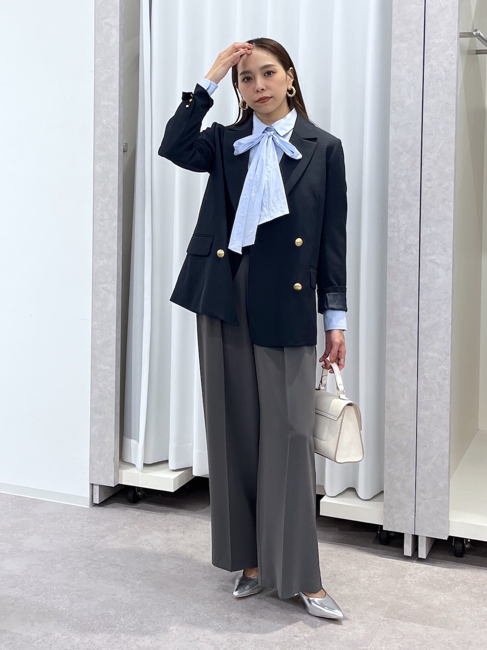 シルバー系のパンプス、グレー系のスラックス、ホワイト系のショルダーバッグを着用したレディースの冬コーディネートの9枚目の写真