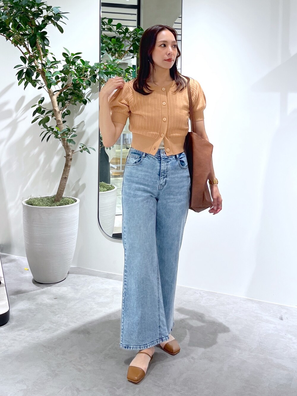 オレンジ系のTシャツ/カットソー、ブラウン系のトートバッグ、ブルー系のデニムパンツを着用したレディースの春コーディネートの4枚目の写真