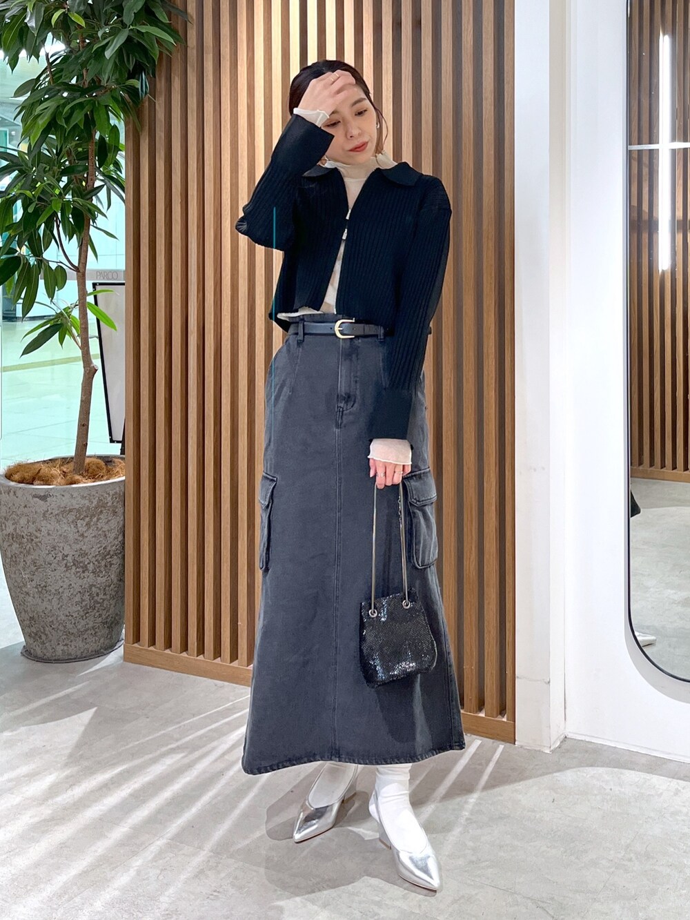 ブラック系のニット/セーター、ホワイト系のTシャツ/カットソー、ブラック系のショルダーバッグを着用したレディースの冬コーディネートの2枚目の写真