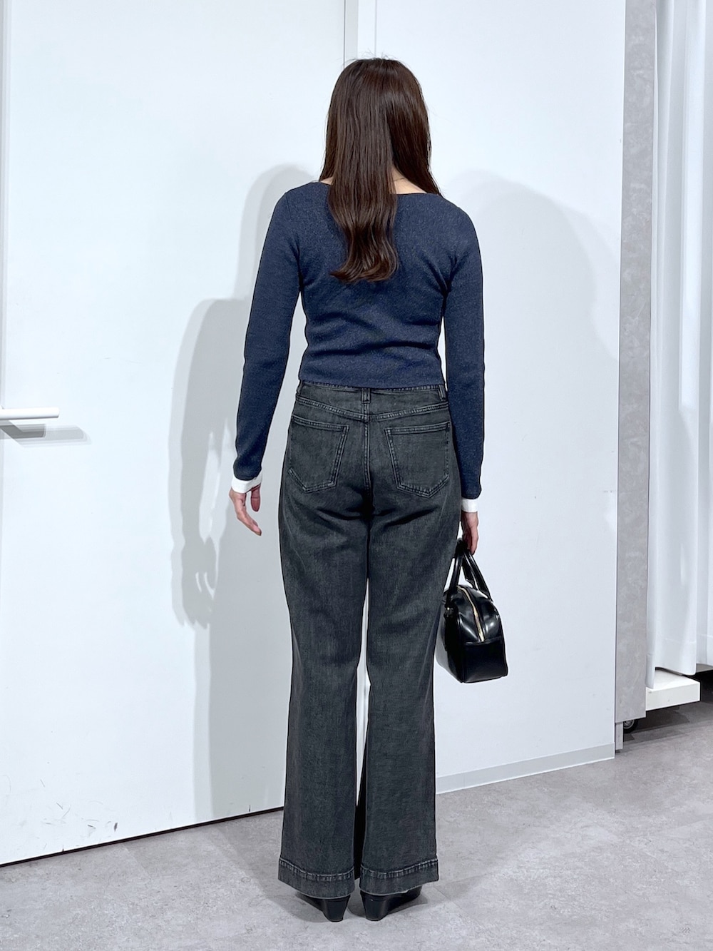 ブラック系のハンドバッグ、ブラック系のパンプス、ブラック系のデニムパンツを着用したレディースの春コーディネートの6枚目の写真