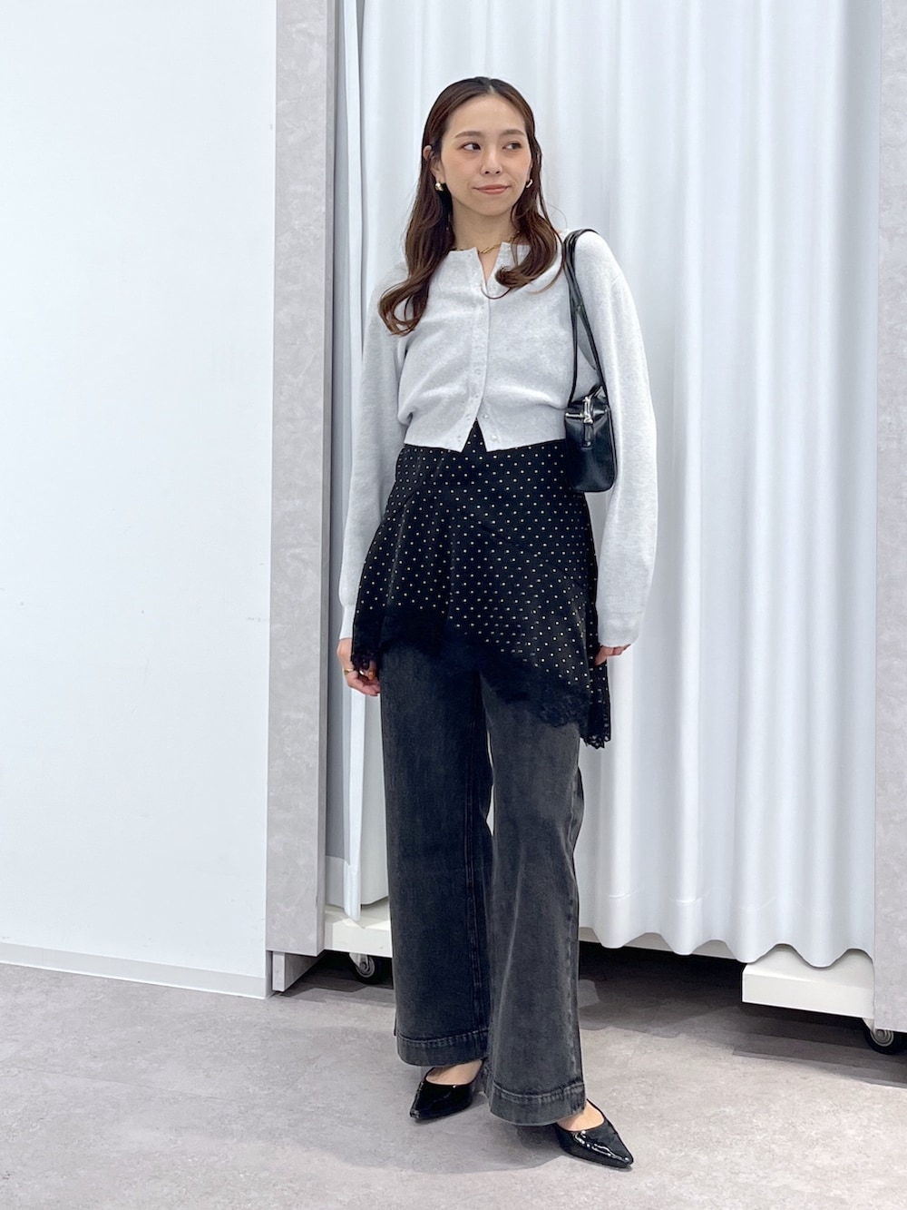 ブラック系のワンピース、ブラック系のデニムパンツ、ブラック系のショルダーバッグを着用したレディースの春コーディネートの6枚目の写真