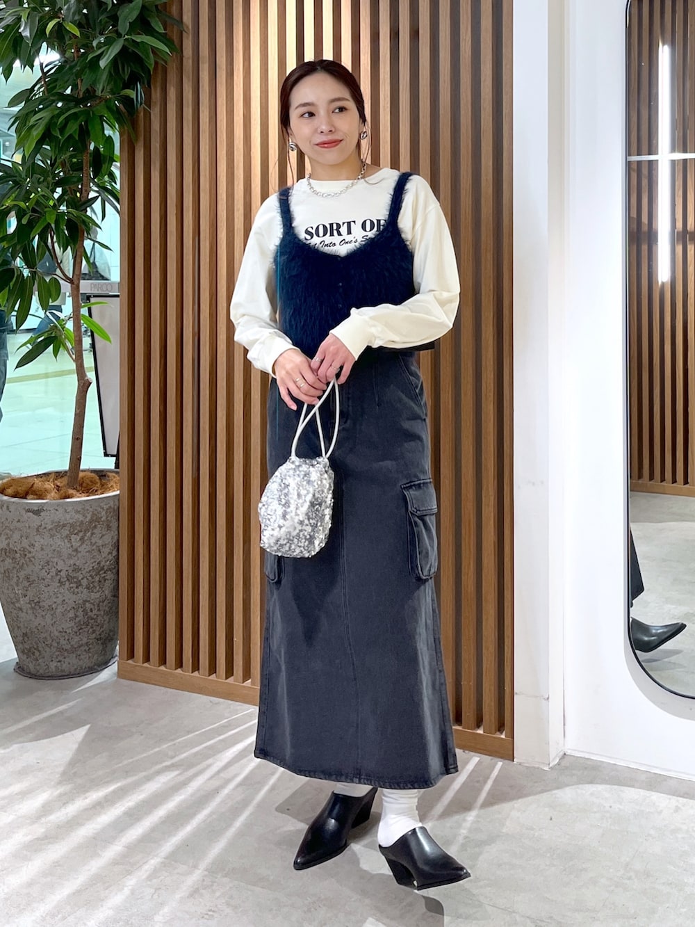 ベージュ系のTシャツ/カットソー、ブルー系のベスト、シルバー系のハンドバッグを着用したレディースの冬コーディネートの6枚目の写真