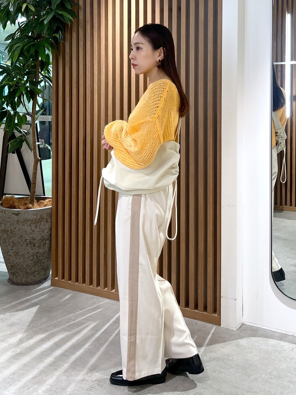 ホワイト系のショルダーバッグ、オレンジ系のニット/セーター、ホワイト系のその他パンツを着用したレディースの冬コーディネートの5枚目の写真