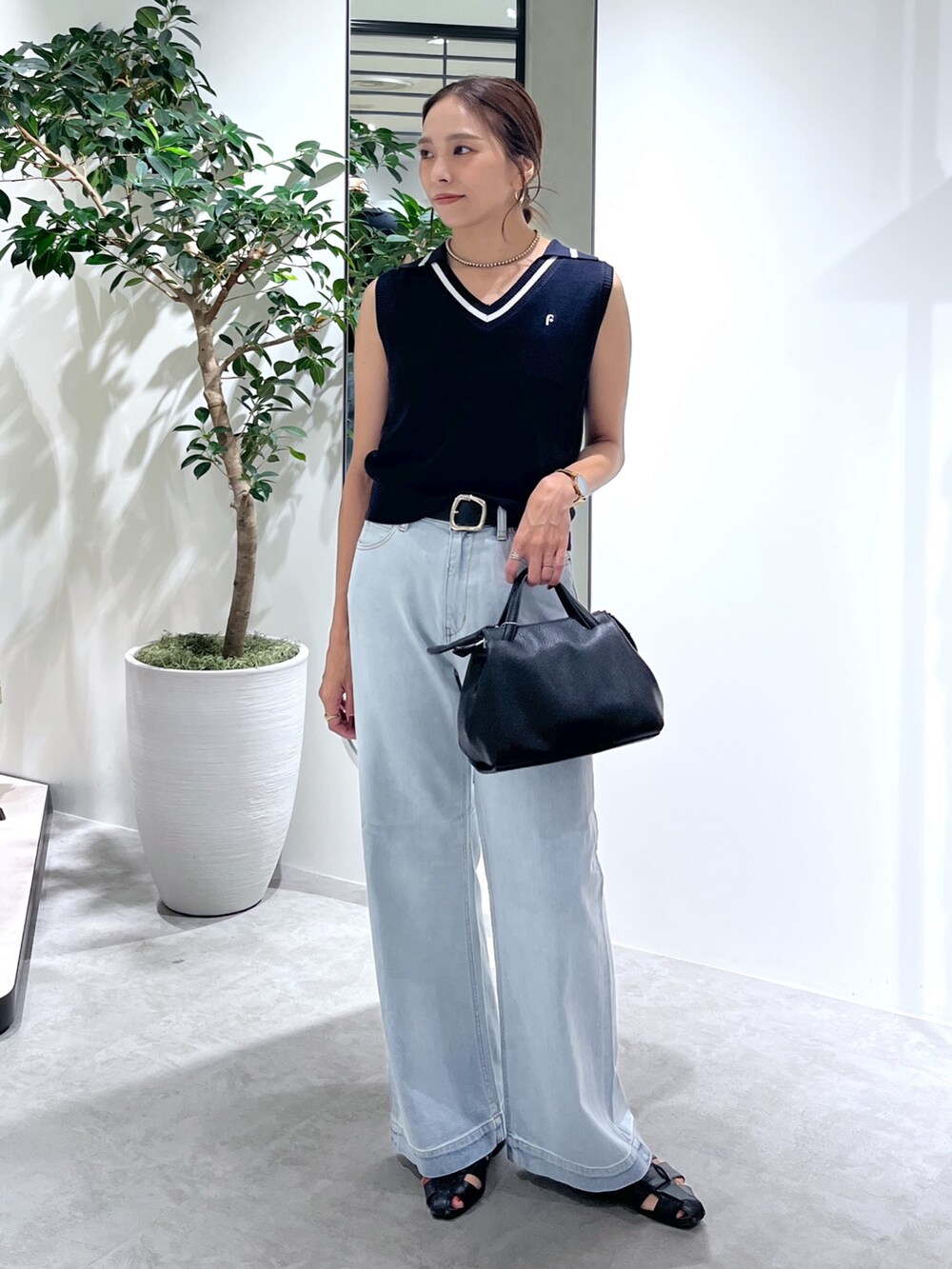 ブルー系のニット/セーター、ブルー系のデニムパンツ、ブラック系のショルダーバッグを着用したレディースの夏コーディネートの6枚目の写真