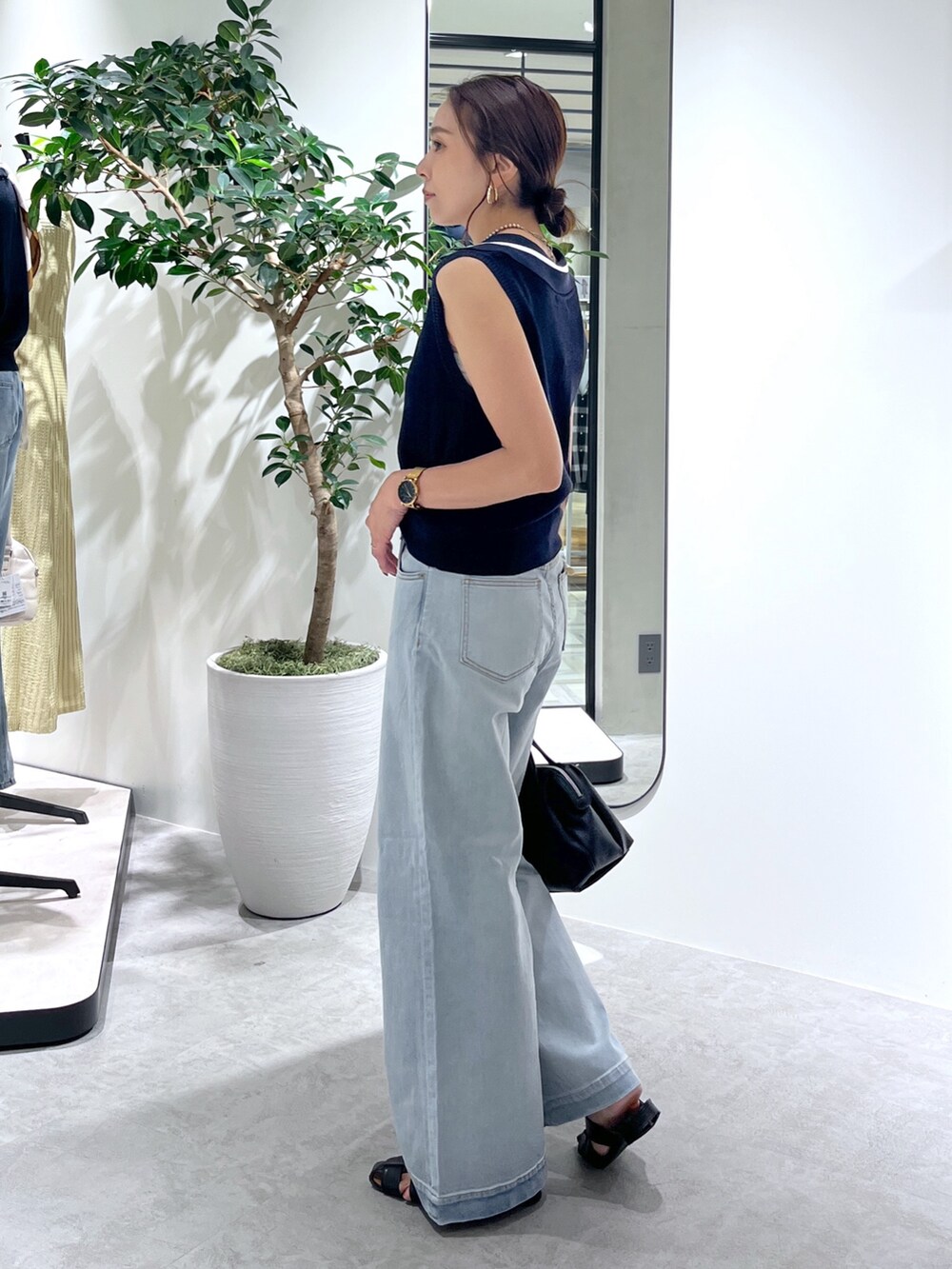 ブルー系のニット/セーター、ブルー系のデニムパンツ、ブラック系のショルダーバッグを着用したレディースの夏コーディネートの4枚目の写真