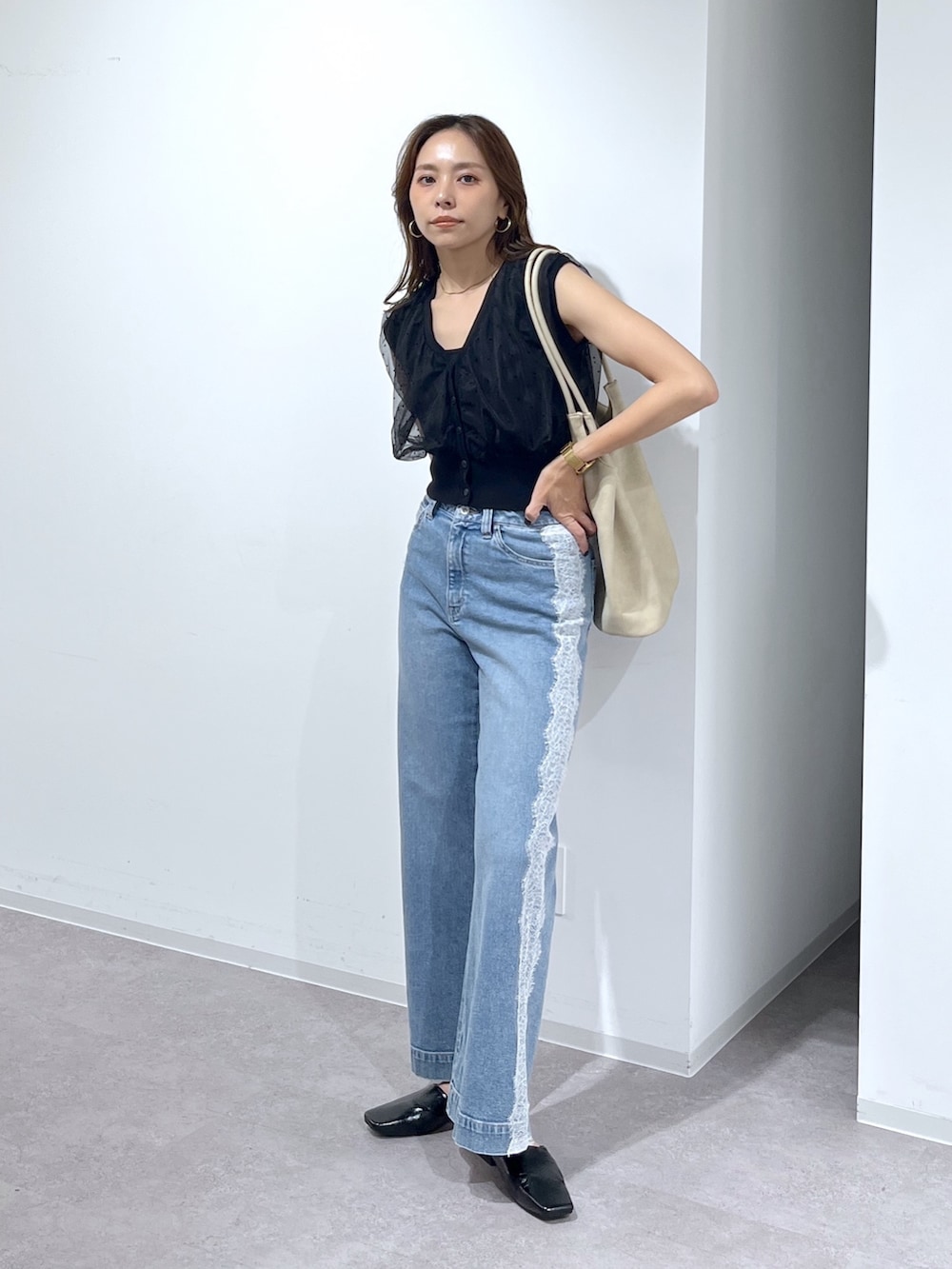 ブラック系のニット/セーター、ブルー系のデニムパンツ、ベージュ系のトートバッグを着用したレディースの夏コーディネートの7枚目の写真