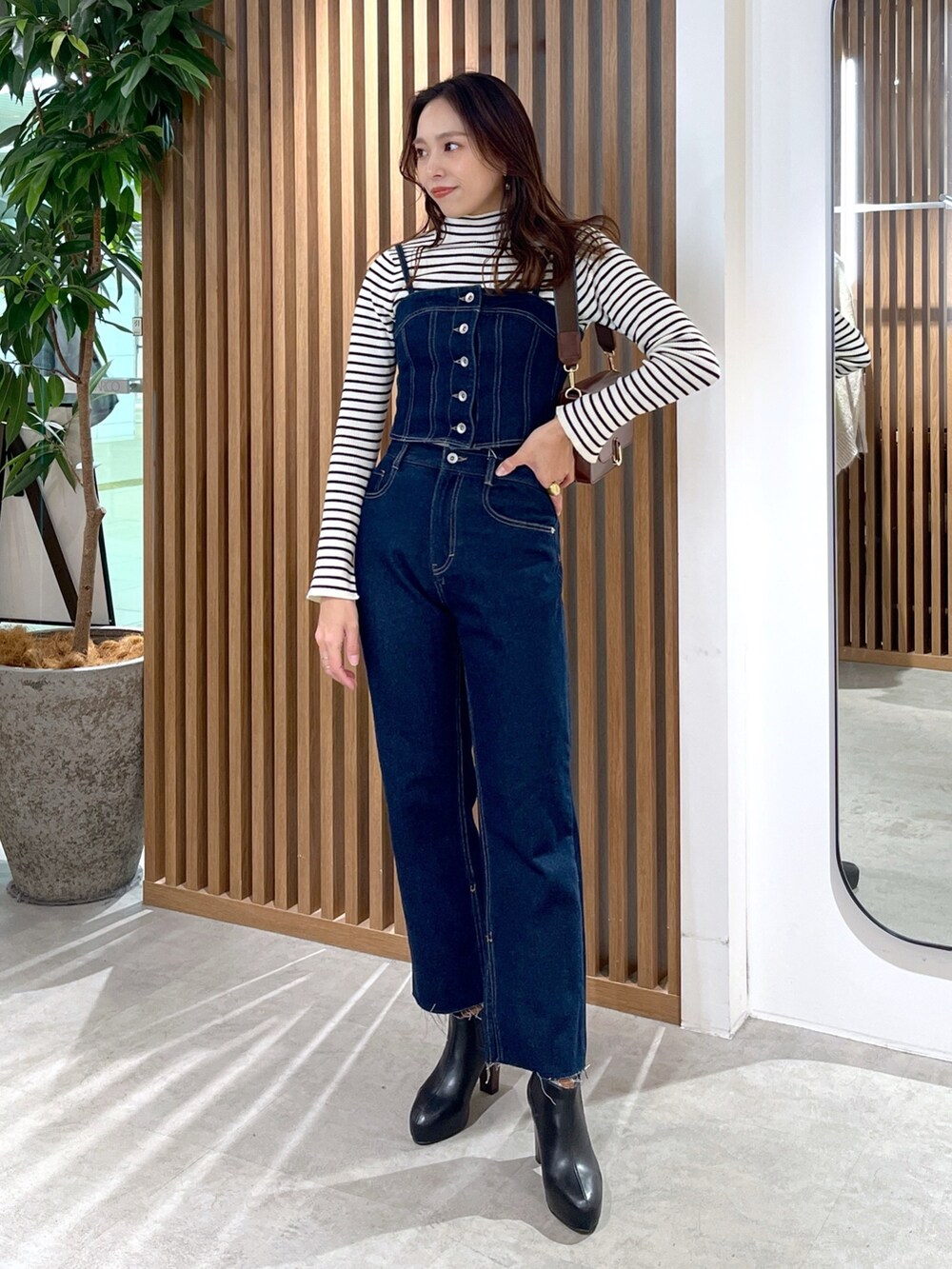 ブラック系のブーツ、ブルー系のデニムパンツ、ブラウン系のショルダーバッグを着用したレディースの冬コーディネートの2枚目の写真