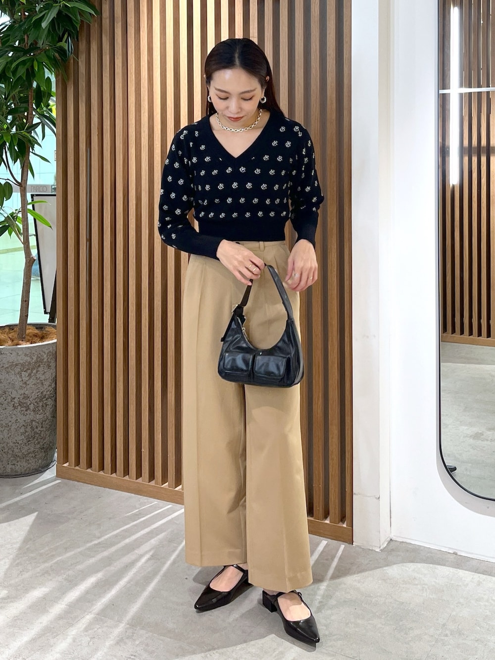 ブラック系のパンプス、ブラック系のショルダーバッグ、ブラック系のニット/セーターを着用したレディースの冬コーディネートの2枚目の写真