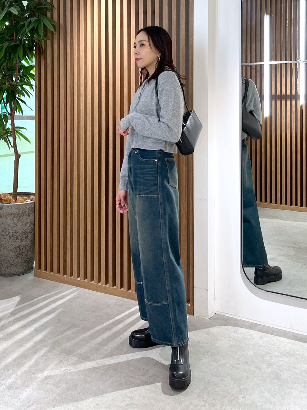 グレー系のワンピース、ブルー系のデニムパンツ、ブラック系のブーツを着用したレディースの冬コーディネートの9枚目の写真