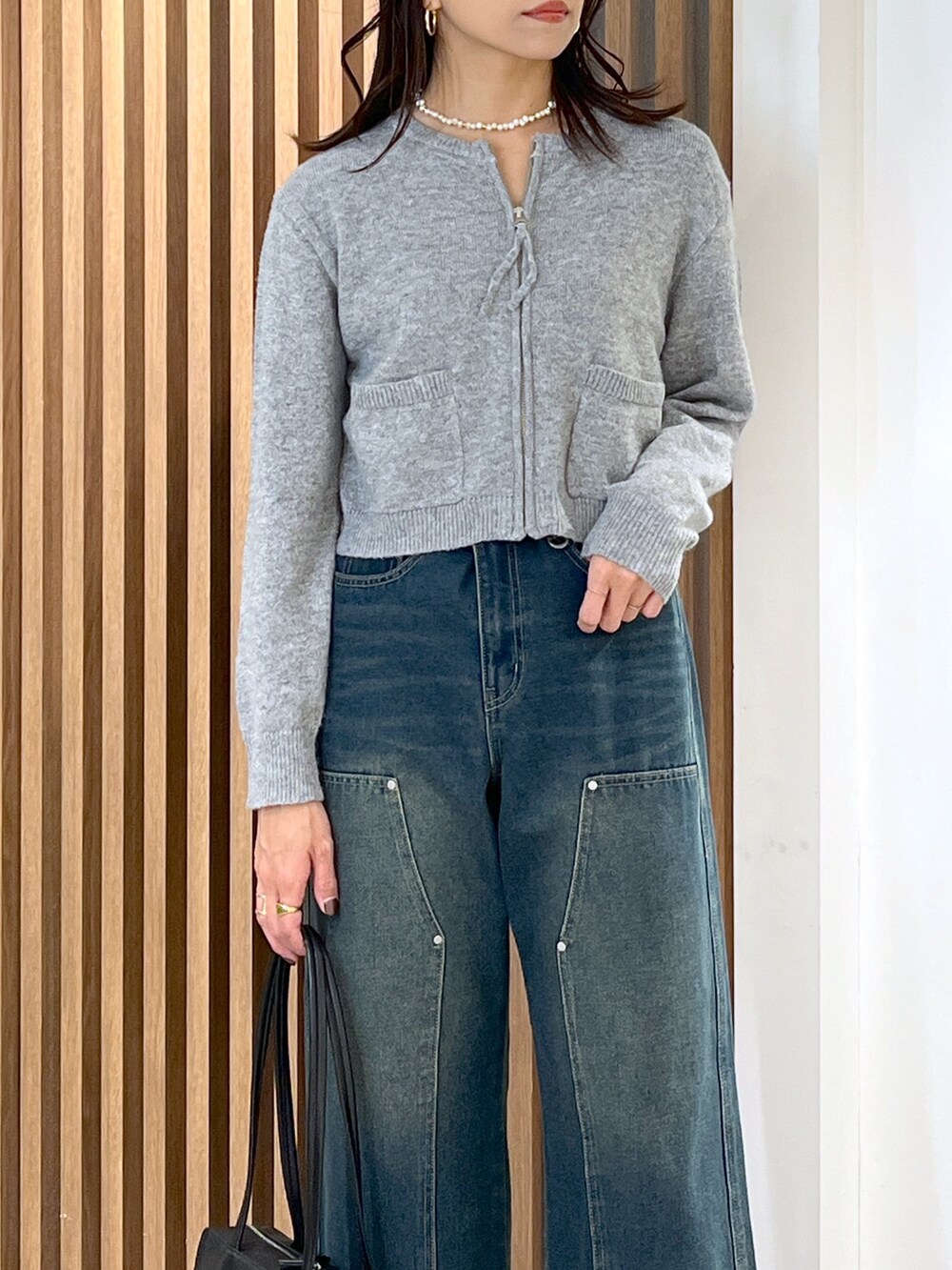 グレー系のワンピース、ブルー系のデニムパンツ、ブラック系のブーツを着用したレディースの冬コーディネートの6枚目の写真