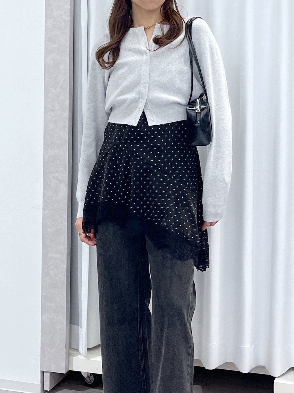 ブラック系のワンピース、ブラック系のデニムパンツ、ブラック系のショルダーバッグを着用したレディースの春コーディネートの5枚目の写真