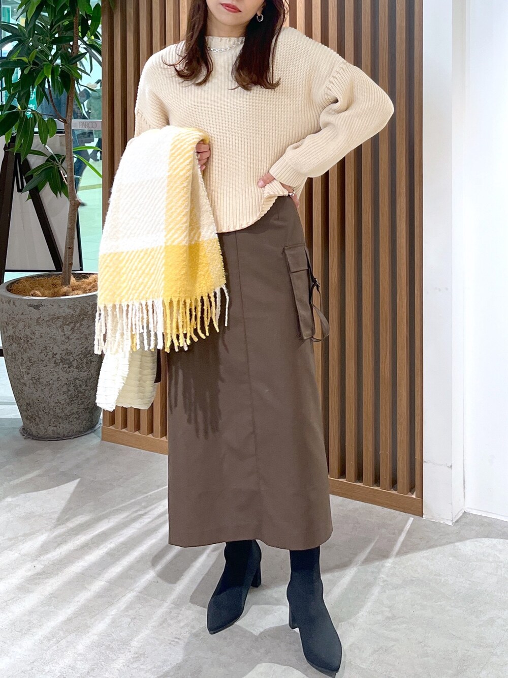 ブラウン系のスカート、ホワイト系のトートバッグ、ホワイト系のニット/セーターを着用したレディースの冬コーディネートの4枚目の写真