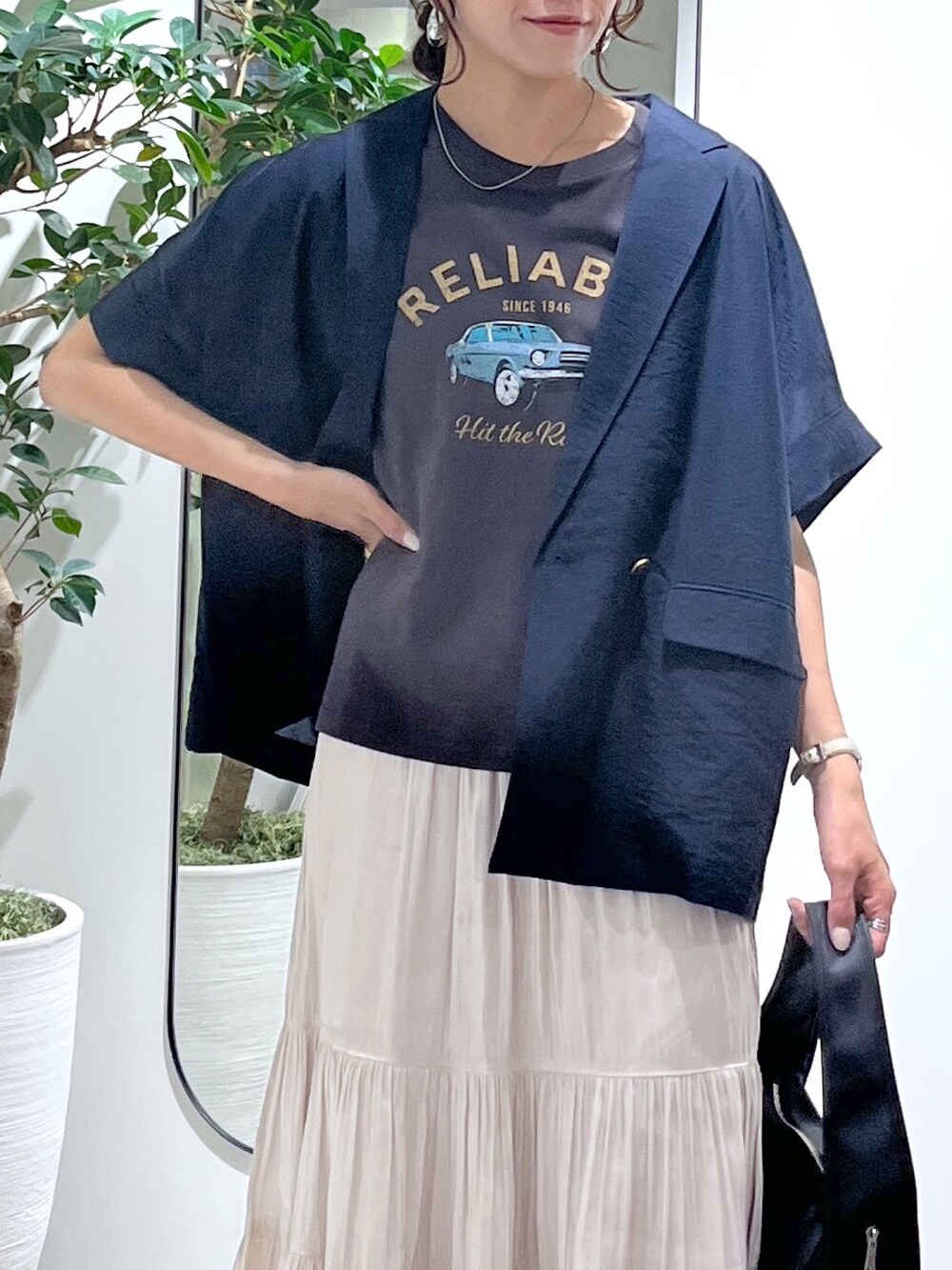 ブルー系のテーラードジャケット、ブラック系のハンドバッグ、ホワイト系のスカートを着用したレディースの夏コーディネートの5枚目の写真