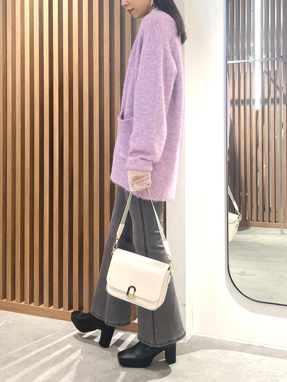 パープル系のカーディガン/ボレロ、ホワイト系のショルダーバッグ、ブラック系のデニムパンツを着用したレディースの秋コーディネートの3枚目の写真
