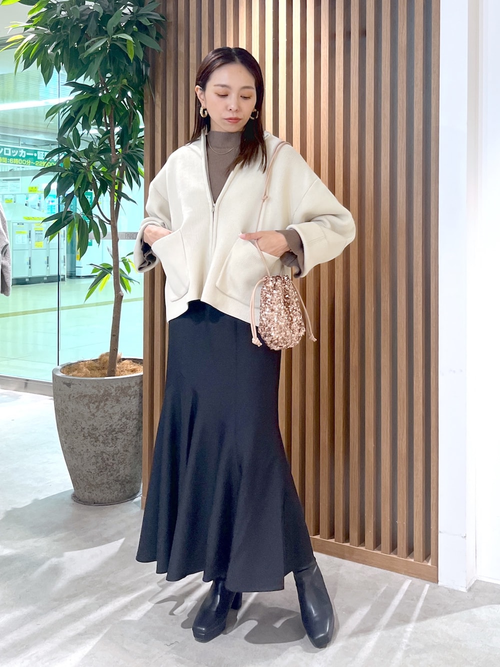 ピンク系のハンドバッグ、ホワイト系のカーディガン/ボレロ、ブラック系のスカートを着用したレディースの秋コーディネートの3枚目の写真